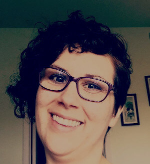 headshot of Amy Pepper wearing glasses and a dark brown curly asymmetrical haircut